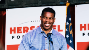 herschel walker standing with sign behind